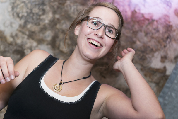 fröhliche, lässige junge Frau in Brille, die lachend und lächelnd eine Party oder Feier genießt - Foto, Bild