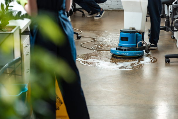 cropped view of cleaner washing floor with cleaning machine near colleagues - Photo, Image