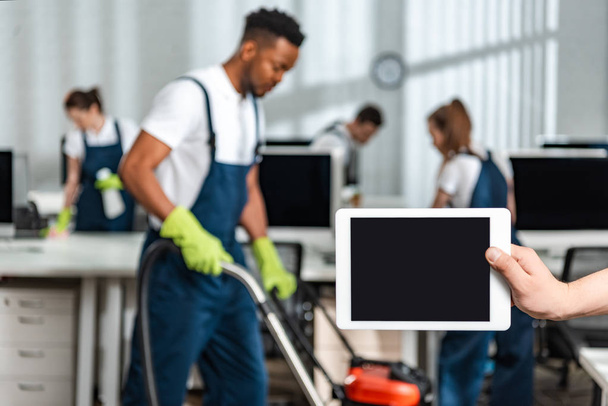 visão cortada do homem segurando tablet digital com tela em branco perto da equipe de limpadores multiculturais
 - Foto, Imagem