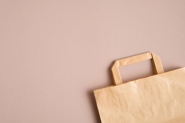Empty kraft paper bag on brown background with copy space. Packaging template mockup - 写真・画像