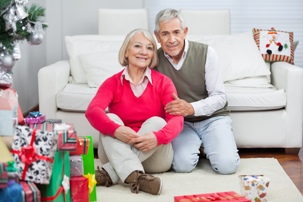 Happy Senior Couple Sitting By Christmas Presents - Фото, изображение