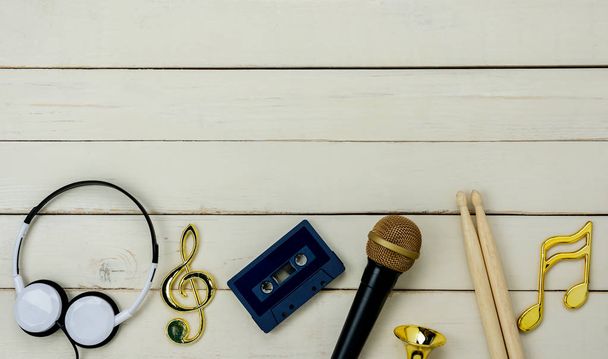 Table top view of music instrument tools concept background.Flat lay of sign to sing for musician or party equipment.microphone headphone note tape cassette and drumstick on modern white wooden. - Φωτογραφία, εικόνα