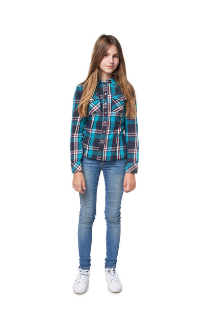 Full length teen girl in checkered shirt standing casually over white background looking at camera - Fotografie, Obrázek
