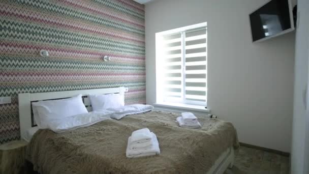 Intérieur d'une spacieuse chambre d'hôtel avec linge frais sur un grand lit double. Chambre contemporaine confortable dans une maison moderne. - Séquence, vidéo