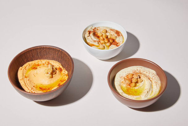 Bowls with delicious hummus on grey background - Photo, Image