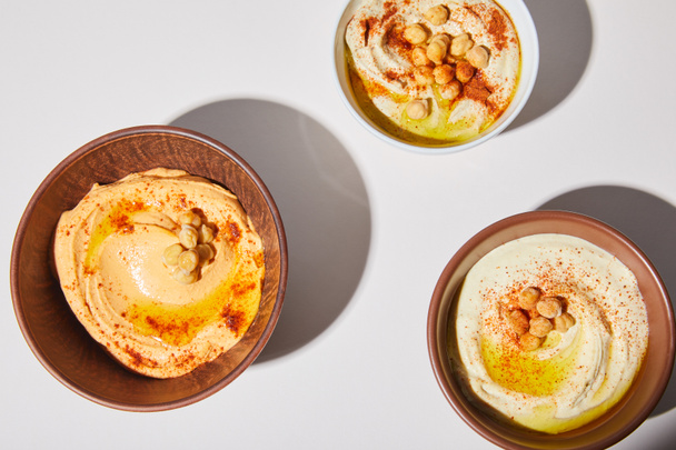 Top view of bowls with hummus and chickpea on grey background - Valokuva, kuva
