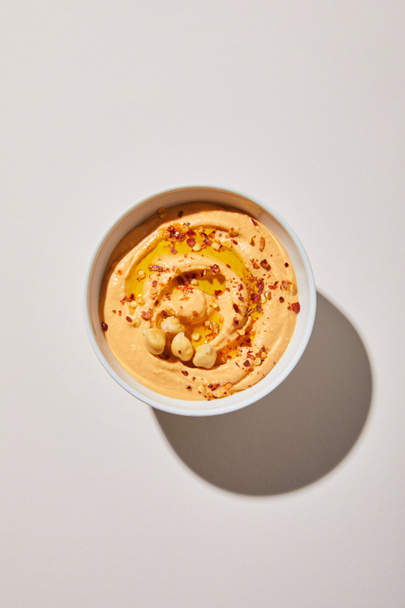 Top view of bowl with delicious hummus on grey background - Zdjęcie, obraz