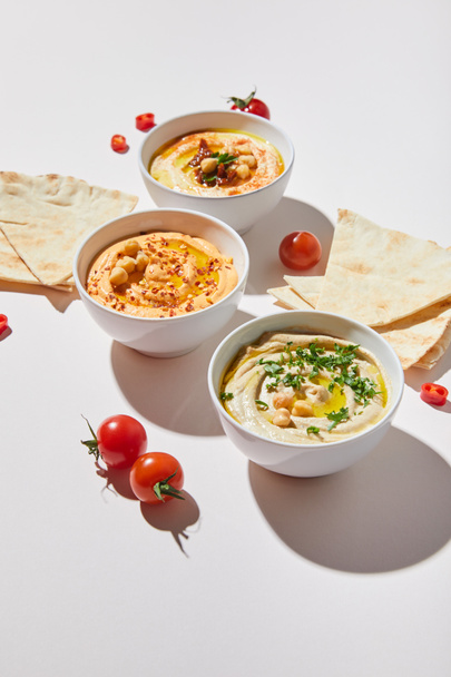 Bowls with delicious hummus, ripe cherry tomatoes and pita bread on grey background - Foto, Bild