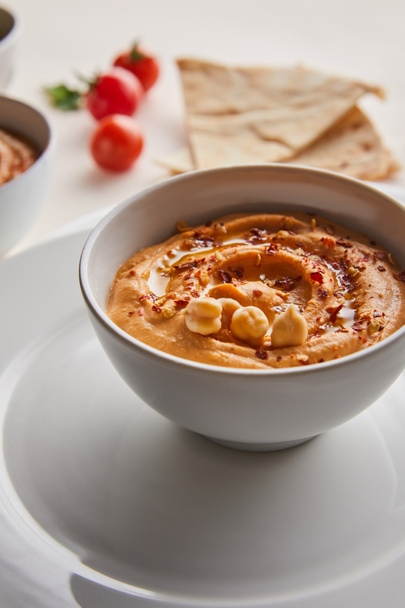 Close up view of bowl with tasty hummus on plate on grey background - Foto, Bild