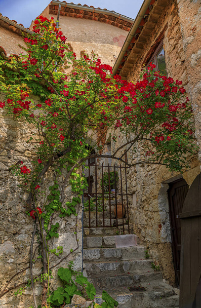 Pedra exterior de edifícios antigos com flores nas ruas de Eze Village, pitoresca cidade medieval no sul da França ao longo do Mar Mediterrâneo
 - Foto, Imagem