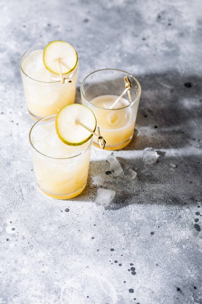 A short glass of refreshing pear soda water mocktail or cocktail on gray concrete background with shadow. Non alcoholic summer drink. Vertical orientation, copy space, top view - Φωτογραφία, εικόνα