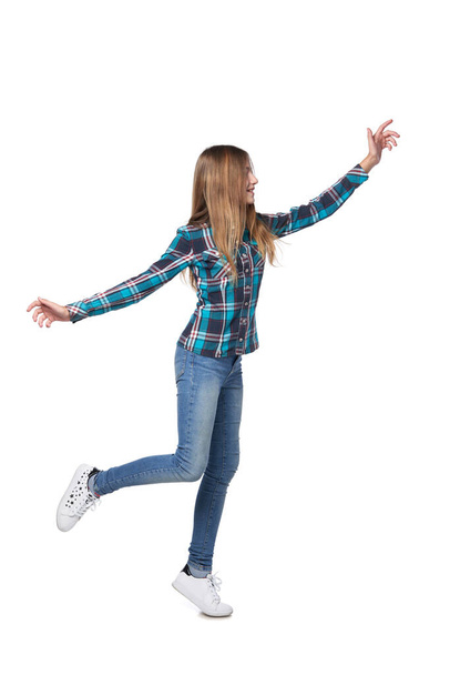Full length smiling teen girl in checkered shirt running hurring over white background - Фото, изображение