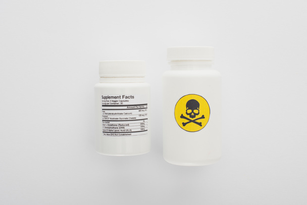 Vista superior de recipientes com suplementos dietéticos e veneno sobre fundo branco
 - Foto, Imagem
