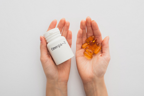 Cropped view of woman holding container with omega-3 lettering and capsules on white  - Photo, Image