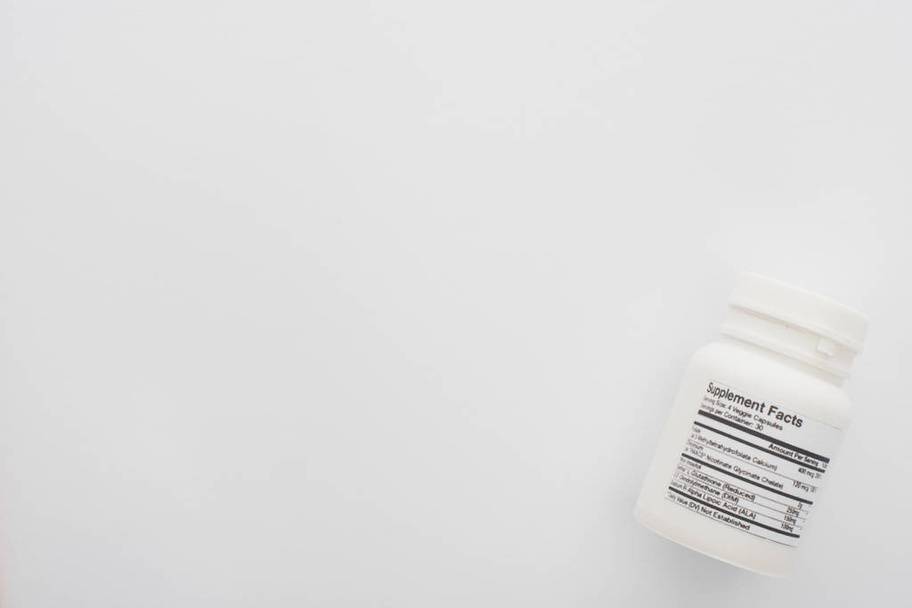 Κάτοψη δοχείου με συμπληρώματα διατροφής σε λευκό - Φωτογραφία, εικόνα