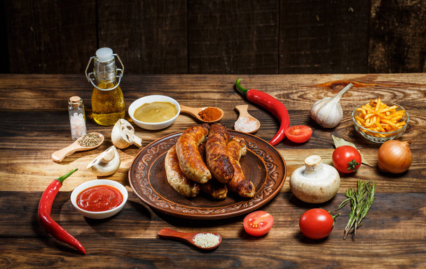 Grilled sausages, fresh vegetables, ingredients and spices on a wooden table - Foto, imagen