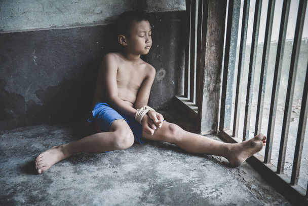 Poszkodowany chłopiec z rąk związany z liny w bólu i stresu emocjonalnego, porwany, nadużywane, zakładników, boi się, ograniczone, uwięzionych, walka, Stop przemocy wobec dzieci i koncepcja handlu ludźmi. - Zdjęcie, obraz