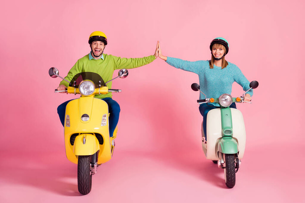 Full body photo of cheerful lady guy drive two vintage moped spend vacation together clap arms one best team wear casual sweater headgear isolated pink color background - Foto, Imagem