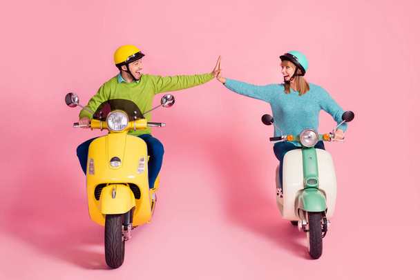 Full length photo of funny cheerful lady guy driving two vintage moped spend vacation together clapping arms one team wear casual sweater headgear isolated pink color background - Foto, afbeelding