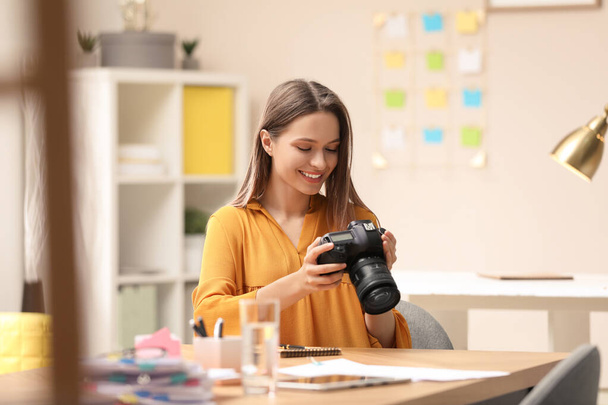 Young journalist with camera at table in office - Photo, image