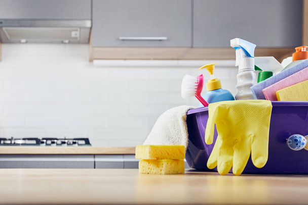 Środki czystości: gąbka, butelka, rękawica, szczotka, spray, szmata na stole i szare tło kuchenne - Zdjęcie, obraz