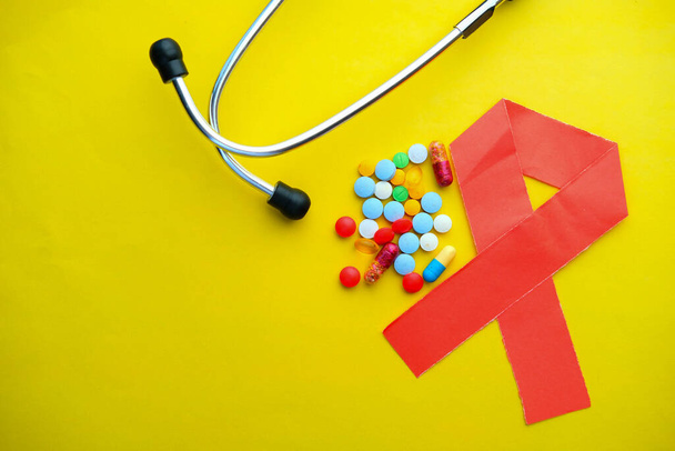 Primer plano del símbolo del VIH y las píldoras sobre fondo amarillo
  - Foto, Imagen
