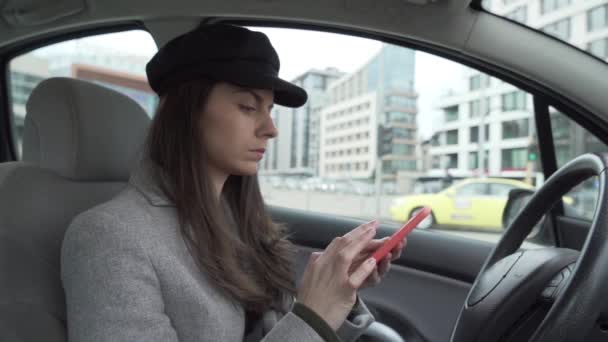 Młoda kobieta w czarnym kapeluszu siedzi w samochodzie i czeka - Materiał filmowy, wideo
