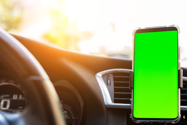 現代のスマートフォンデバイスガジェットは、車のダッシュボードで携帯電話ホルダーにマウントされています。モックアップ緑のクロマキー画面の隔離テンプレート。テキスト用のコピースペース。車内コックピットビュー。交通渋滞情報アプリ. - 写真・画像