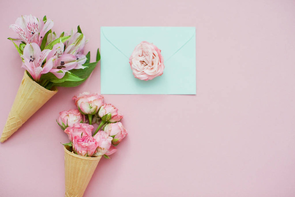 Ice cream cones with pink flowers and mint envelope on pink pastel background. Top view - Foto, immagini