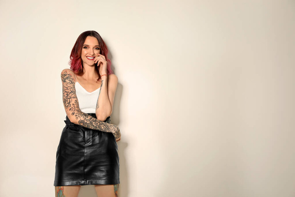 Beautiful woman with tattoos on body against light background. Space for text - Zdjęcie, obraz