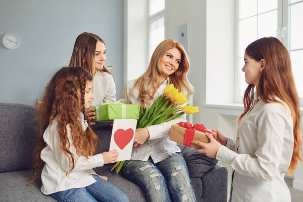 Happy Mothers Day. Children daughters give mom a bouquet of flowers at home. - Foto, Bild