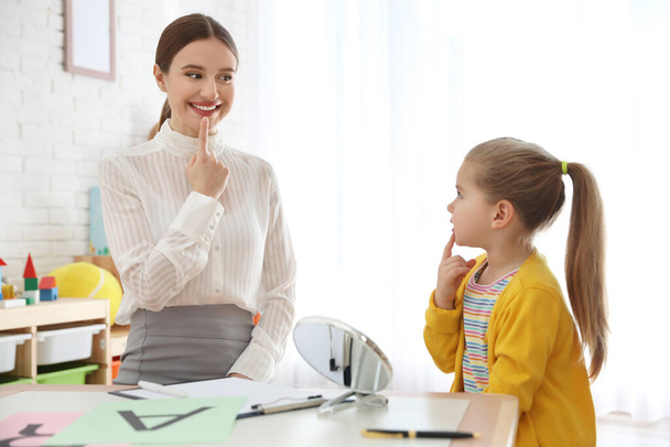 Speech therapist working with little girl in office - Foto, afbeelding