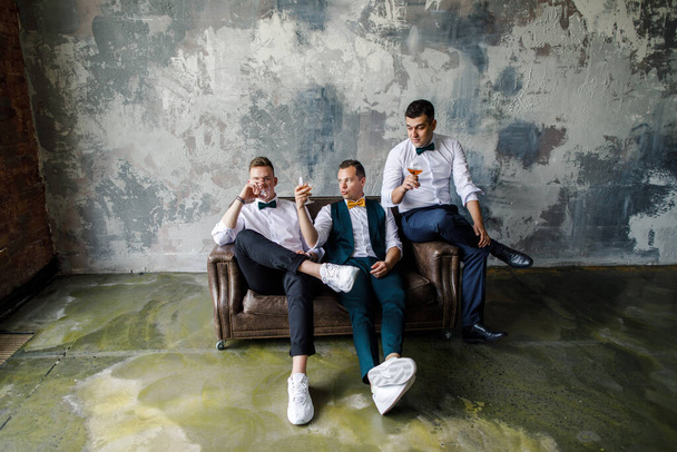 three men in a white shirt drink whiskey in glasses in a loft apartment - Foto, imagen