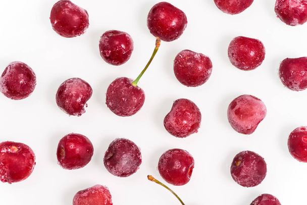 group of frozen cherries on a white background throughout the photo. the view from the top. pattern. close up. ice crystals on the fruit - Foto, Imagem