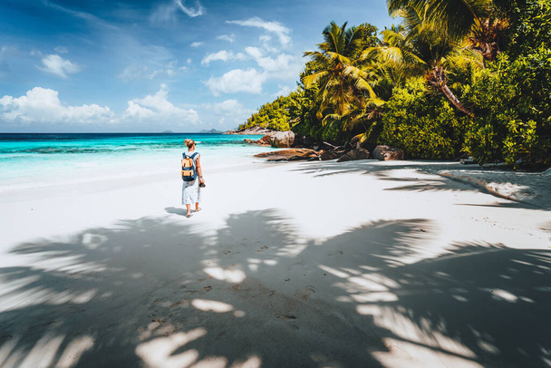 Female tourist enjoy empty tropical beach on vacation. White sand beach, palm trees and blue ocean lagoon. Exotic paradise recreation vacation concept - Fotó, kép