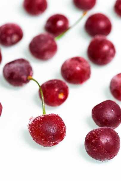 frozen cherry on a white background . ice crystals on the berry. vertical photo - 写真・画像
