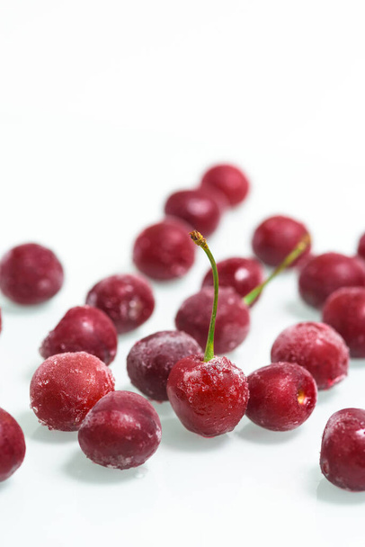 group of frozen cherries on a white background . ice crystals on the berry. vertical photo - Φωτογραφία, εικόνα