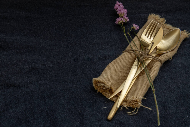 A set of bronze cutlery, spoon, fork and knife black background. Copy space, Selective focus. - Photo, Image