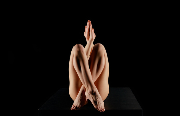 young woman with crossed legs practicing yoga isolated on black  - Photo, Image