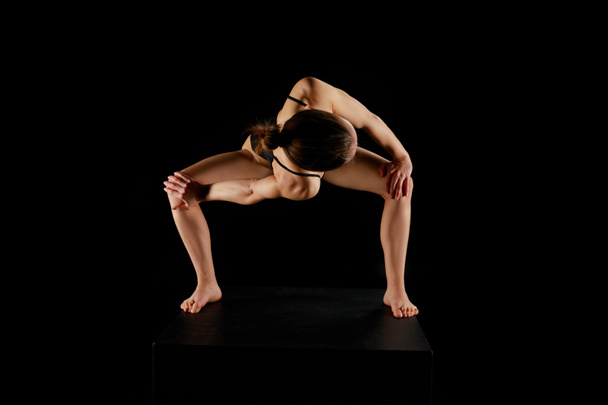fille avec pieds nus faisant tour lié angle latéral exercice isolé sur noir
  - Photo, image