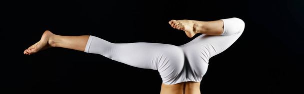 panoramic shot of young woman in white sportswear doing handstand isolated on black  - Foto, Bild