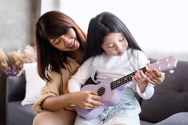 Мати викладає укулеле з прекрасною дочкою, у студії музичної кімнати, сімейної діяльності, з радісним почуттям. - Фото, зображення
