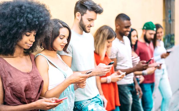 Багатокультурні друзі групуються під час наркоманії за допомогою мобільних смарт-телефонів - молодих людей, загіпнотизованих соціальними мережами - концепція технологій з завжди пов'язаними тисячоліттями - фільтр Вівіда. - Фото, зображення