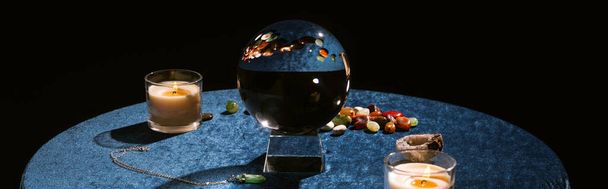 Хрустальный шар, свечи и фортуна говорят камни на темно-синем велюре ткани, панорамный выстрел
 - Фото, изображение