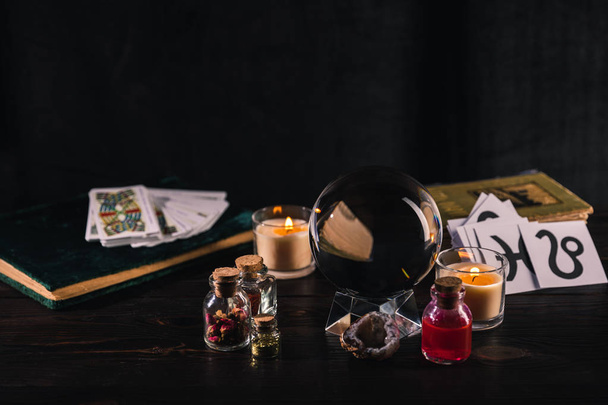 KYIV, UKRAINE - JANUARY 9, 2020: selective focus of tarot cards and crystal ball with occult objects on wooden and black background - Foto, afbeelding