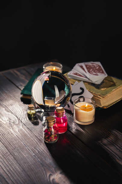 KYIV, UKRAINE - JANUARY 9, 2020: selective focus of crystal ball, candles and occult objects on wooden and black background - Foto, Imagem