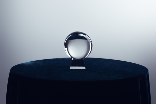 Kryształowa kula na okrągłym stole na szarym tle - Zdjęcie, obraz