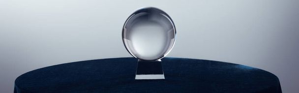 Bola de cristal sobre mesa redonda sobre fondo gris, plano panorámico
 - Foto, Imagen