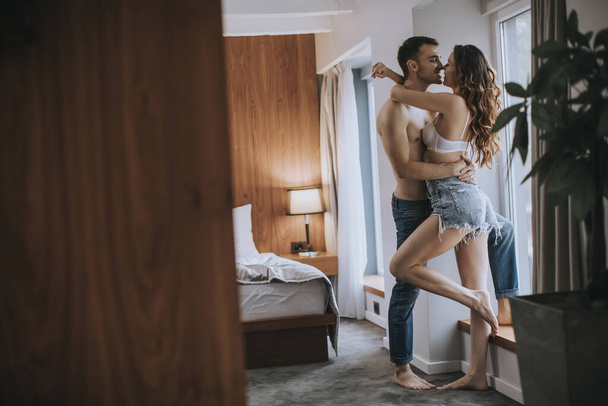 Casal jovem afetuoso em pé junto à janela no quarto do apartamento - Foto, Imagem