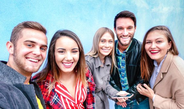 Beste vrienden die selfie dragen vier seizoensgebonden kleding - Happy lifestyle concept met millenial mensen die plezier hebben samen buiten - Dagelijks leven van de volgende generatie jongens en meisjes op levendige filter - Foto, afbeelding